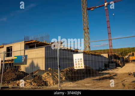 Construction site with concrete foundation and tower cranes behind safety fence.Blue sky in background Stock Photo