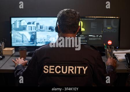 Middle Aged Man Monitoring Security Cameras in Control Room Stock Photo