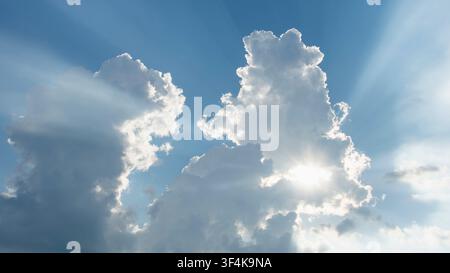 Sun shining through white puffy clouds Stock Photo