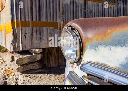 Close-up of abandoned car next to sheet metal building Stock Photo