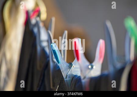 Close-up of plastic colored clothespins attached to clothing hanging on a line at sunset golden hours Stock Photo