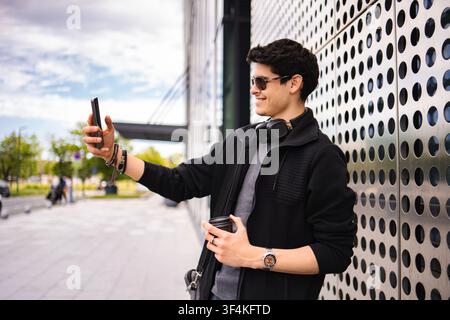 Young adult man using smartphone video calling on city street Stock Photo