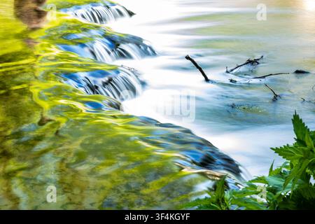 Small waterfall with silky flowing water in a forest stream captured with long exposure Stock Photo