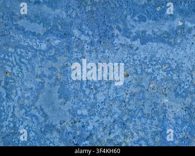 Close-up of a weathered, rough concrete or stone surface with a mottled light blue texture, tiny pits, and uneven color variations. Stock Photo