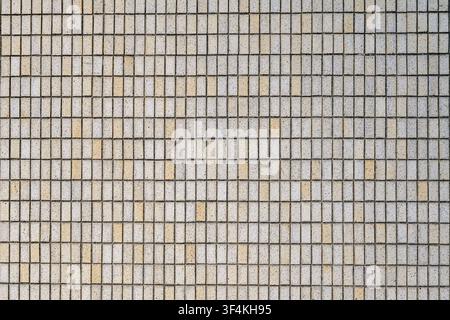 Small concrete tiles form a repeating grid on an urban building facade Stock Photo