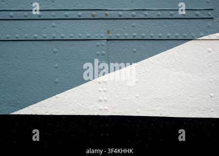 Weathered painted metal panels in blue grey and white form a diagonal geometric composition Stock Photo