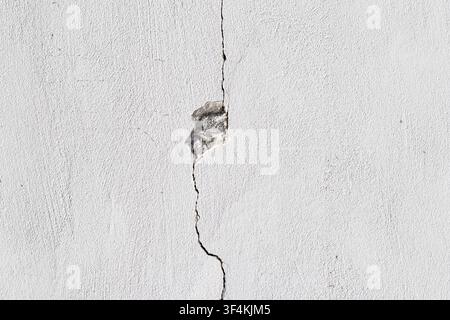 cracked white concrete wall texture with damaged cement surface and hole Stock Photo