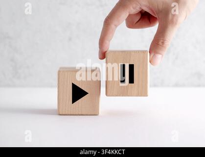 Hand holding a wooden pause block, representing the concept of taking a break, mental health, and work life balance Stock Photo
