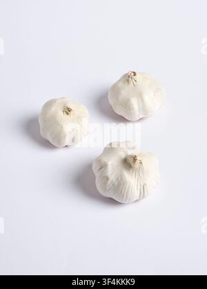 Three fresh, whole garlic bulbs displaying natural texture and color, resting on a clean white surface for food related projects Stock Photo
