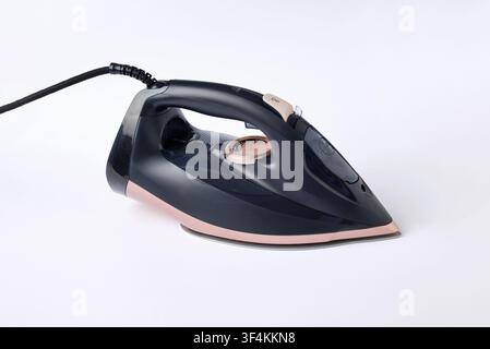 Studio product shot of a modern electric steam iron with rose gold accents isolated on a clean white background representing garment care and househol Stock Photo