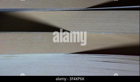 Stacked books revealing aged paper texture with contrasting light and shadow Stock Photo