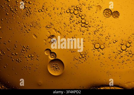 Golden oil droplets floating in water creating an abstract background texture Stock Photo