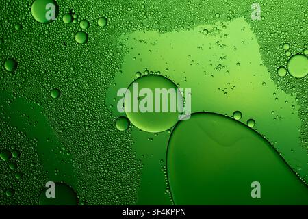 Oil drops creating an abstract pattern on a green liquid surface, macro view Stock Photo