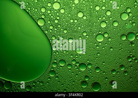 Green oil bubbles forming intricate patterns on water, creating an abstract liquid background Stock Photo