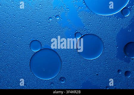 Oil drops on water surface creating blue abstract background with bubbles and texture Stock Photo