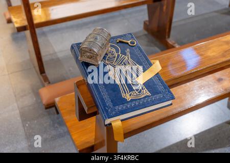 Religious book, ornate casket, and golden key resting on a wooden church pew, symbolizing faith and wisdom Stock Photo