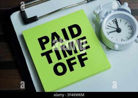 Concept of paid time off write on sticky notes isolated on Wooden Table. Stock Photo