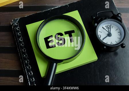 Concept of EST - Earliest Starting Time write on sticky notes isolated on Wooden Table. Stock Photo