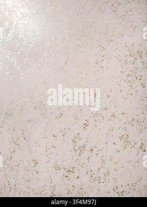 A textured cream wall appears weathered by subtle gold and taupe marks, photographed close-up with even lighting. The image fits decor, construction Stock Photo