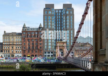 The South Portland Street Suspension Bridge with the Virgin Hotel Glasgow, a 17-story hotel located on Clyde Street Stock Photo