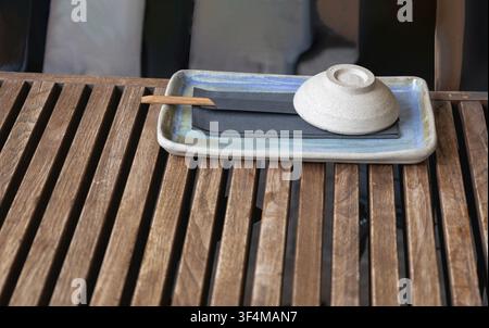 Modern ceramic bowl and chopsticks on a wooden table at a restaurant Stock Photo