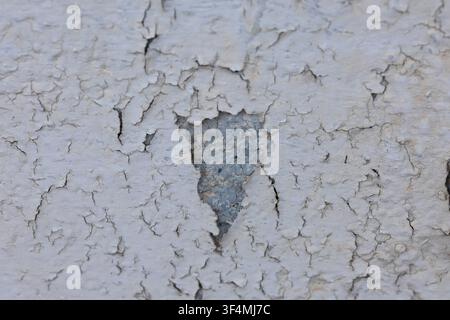 White paint peeling from an aged wall creating a distressed background texture Stock Photo