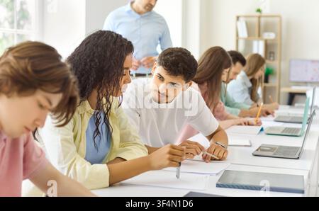 Diverse students collaborating in classroom during university lecture with teacher Stock Photo