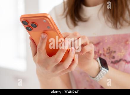 Kyiv, Ukraine. July 29, 2026. Close-up of a woman's hands holding and interacting with an orange iPhone 17 Pro Max. Focus on back camera. Stock Photo