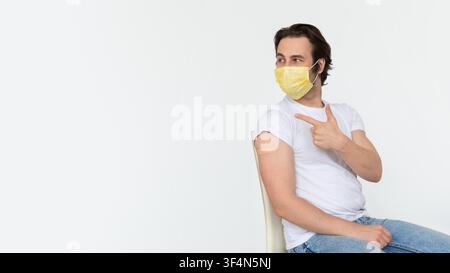 Young Man Getting Vaccination In Clinic, Wearing Mask, Healthcare Concept Stock Photo
