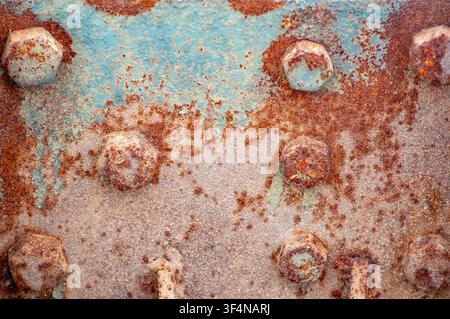 Close-up texture of weathered metal with rust and peeling blue paint and bolts Stock Photo