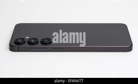 Modern dark gray smartphone with triple camera lenses on a clean white background Stock Photo