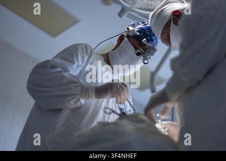 professional neurosurgeon is working in the operating room. medical team of surgeons performing intricate procedure in sterile hospital operating room Stock Photo