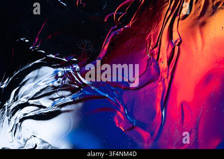 Abstract liquid surface moving with dynamic red, blue, and purple light reflections creating waves and ripples Stock Photo