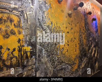 A detailed close-up photograph of a contemporary mixed media relief artwork or wall sculpture. The piece features a dominant golden-yellow background Stock Photo