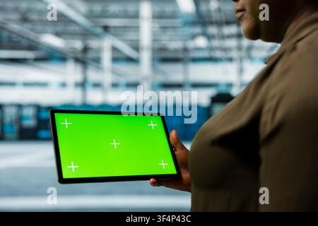 Data center system administrator using green screen tablet to automate anomaly detection. Server room IT specialist using chroma key device, minimizing downtime through predictive maintenance Stock Photo