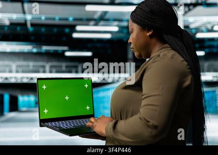 Close up of data center engineer using isolated screen laptop to optimize network hardware, planning capacity. IT expert manages server hub resources with chroma key notebook for improved reliability Stock Photo