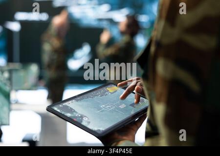 Close up of tablet used by soldier to look at satellite imagery, using touchscreen interface controls in command center. Military operator reviews tactical information on device screen Stock Photo