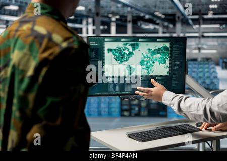 Close up of teamworking military experts in data center pointing to regions of interest on map. Army colleagues in server farm analyzing worldwide threat indicators, coordinating resource allocation Stock Photo