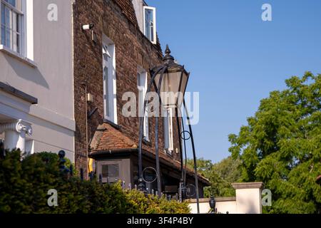 Vintage black street lamp outside traditional brick residential buildings under a blue sky. Stock Photo
