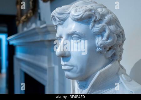White marble bust sculpture of a man in profile against an interior background. Stock Photo