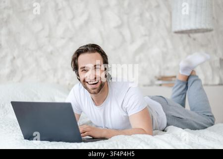 Happy Young Caucasian Man Working On Laptop At Home, Relaxed Lifestyle Concept Stock Photo