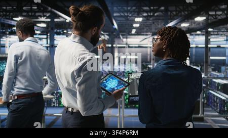 Server farm manager overseeing workers doing infrastructure AI machine learning automatization. Data center team leader supervising employees using artificial intelligence, Stock Photo