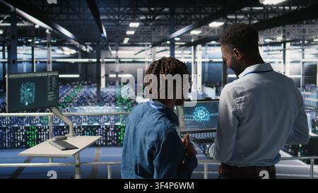 Data center engineering team doing maintenance on rigs handling AI processing tasks. Server hub teamworking colleagues managing storage arrays supporting deep learning training workflows, Stock Photo