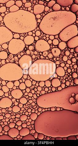 Oil and water forming abstract orange and pink bubbles on a liquid surface Stock Photo