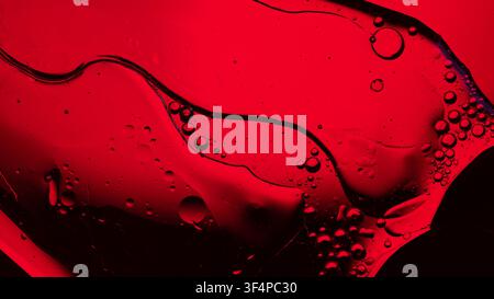 Red liquid with oil and water creating a textured abstract background with bubbles Stock Photo
