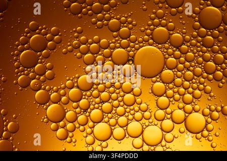 Oil and water creating an abstract golden bubble background with varying sizes Stock Photo