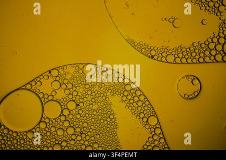 Oil and water forming abstract yellow liquid bubbles and patterns Stock Photo