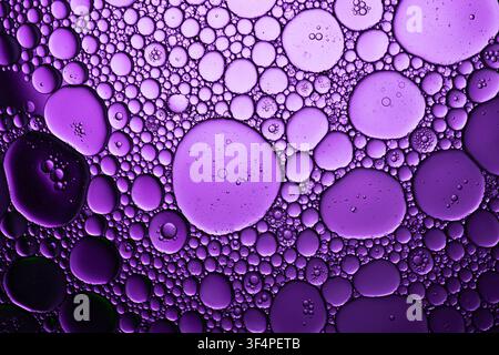 Oil and water separating creating purple bubbles and circles with an abstract pattern Stock Photo