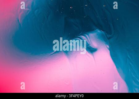 Abstract liquid surface showing merging vibrant blue and pink color gradients with small bubbles Stock Photo