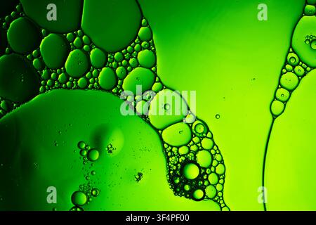 Green oil bubbles mixing with water, forming abstract texture and patterns Stock Photo